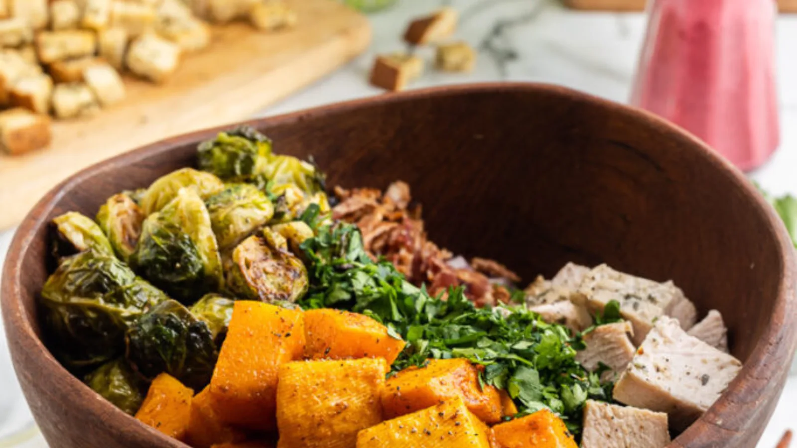 A bowl of salad with butternut squash, turkey and brussels sprouts.