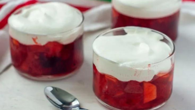 Cups of cranberry jello salad with whipped cream.