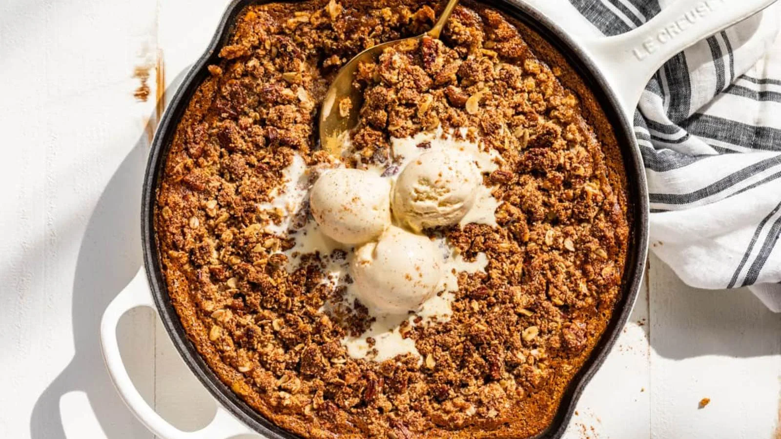  A skillet of pumpkin crisp with ice cream scoops.