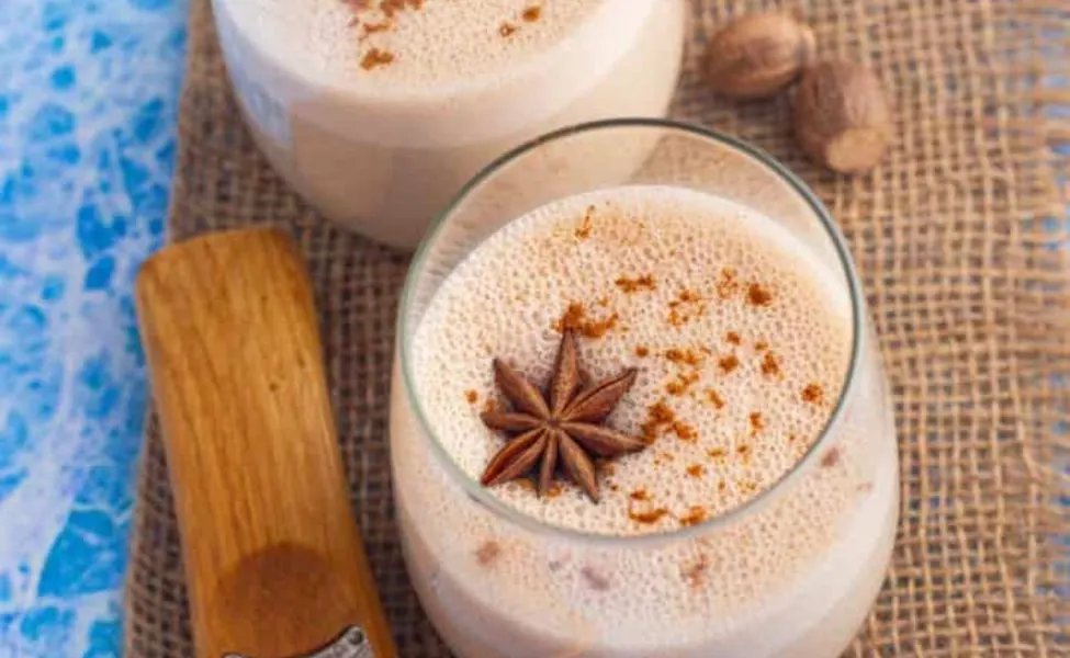 A glass of cashew eggnog with anise on top.