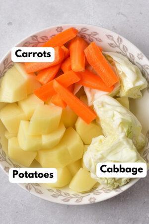 a bowl with cabbage, carrots, and potatoes
